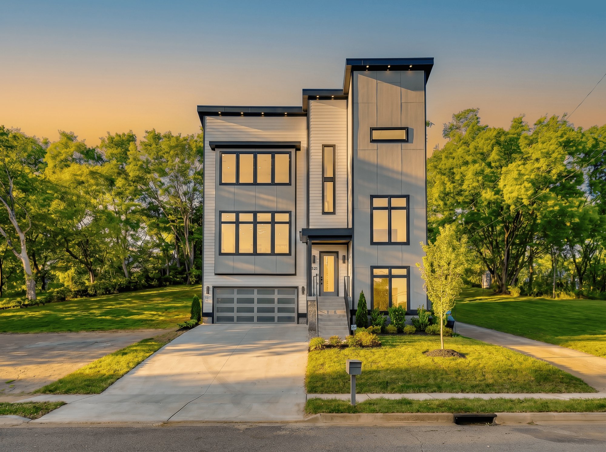Three-story modern new construction home with tall black-framed windows at golden hour